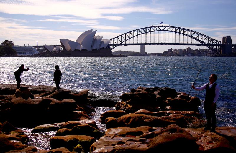 资料图片：2018年11月，澳洲悉尼，游客在悉尼湾大桥和歌剧院附近拍照。REUTERS/David Gray